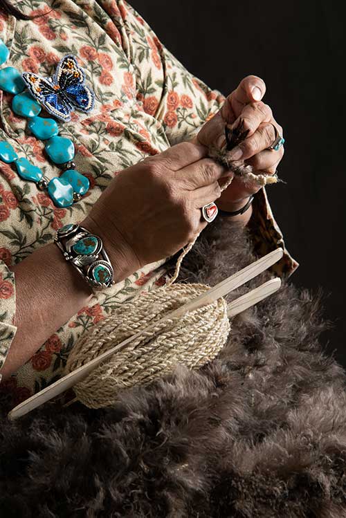 Photo of Mary Weahkee,weaving a blanket with thousands of feathers from turkey hunters
