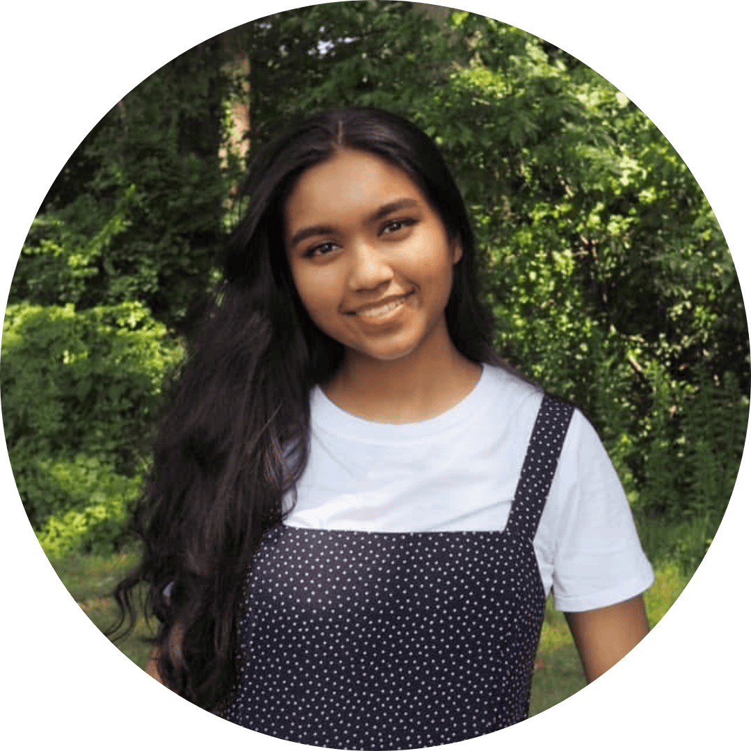 Nabeeha smiles in front of a wooded background.