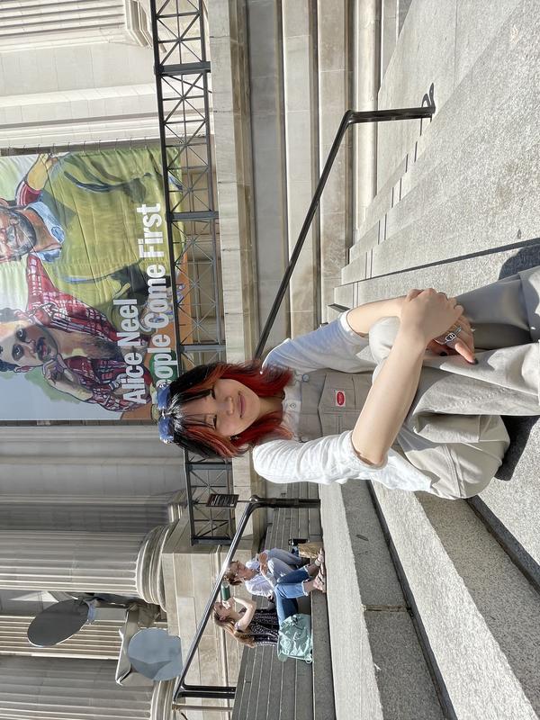 Liz sitting on steps in front of the Met, smiling at the camera.