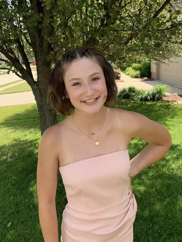 Skyler Evans smiling at the camera standing in front of a tree