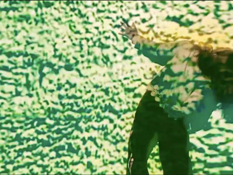 Blurry image of a person dancing with their left arm extended and their body leaning in the opposite direction. Their long brown hair swings to the right. There is a green, grasslike overlay to the image. Credit is as follows: Clock: February 2021 (Time as Self), created by Allison Costa. Generated with the support of elektron.art's "fruitful misunderstandings" residency.