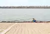 A girl crouching near a waterfront